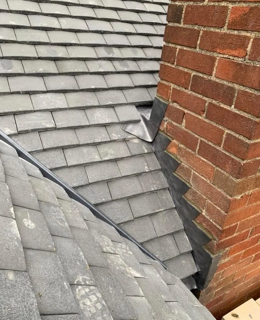 Lead flashing dressed around a brick chimney on a tiled slope, Imperial Roofcraft roofing job in London
