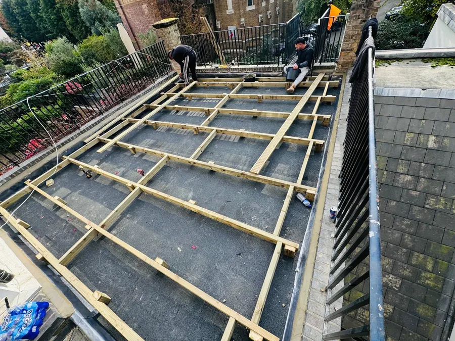 Roofers fixing timber firrings over an old felt flat roof, Imperial Roofcraft roofing job in London